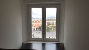 Ein Zimmer mit großem Fenster und Blick auf die Stadt.