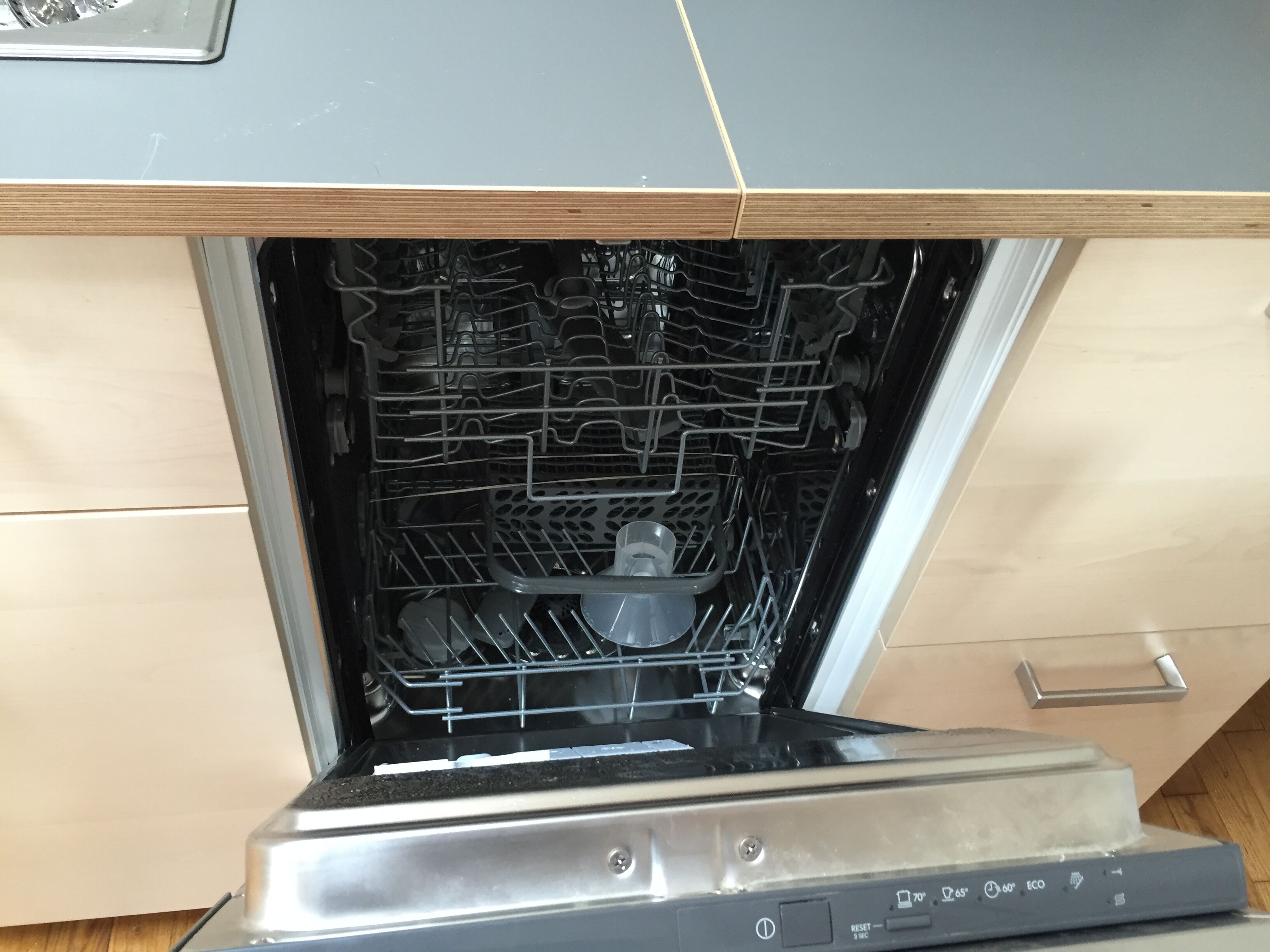 An open dishwasher with multiple racks and a control panel.