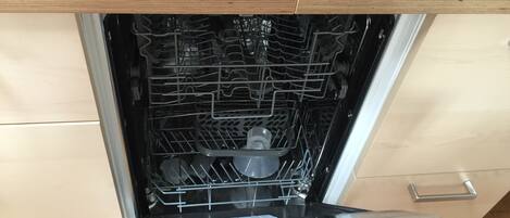 An open dishwasher with multiple racks and a control panel.