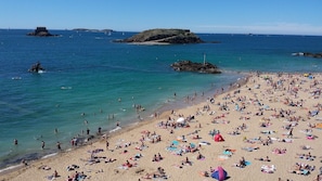 A crowded beach with clear blue water, rocky outcrops, and boats in the distance. - Proche Plage & remparts, T1bis, terrace, Wifi, parking space, bed made (Saint-Malo)