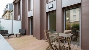 An outdoor patio with wooden furniture, a sliding glass door, and a small enclosed area with a bench. - Proche Plage & remparts, T1bis, terrace, Wifi, parking space, bed made (Saint-Malo)