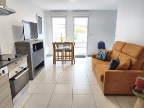 Une cuisine moderne avec un coin repas, un canapé et un téléviseur.