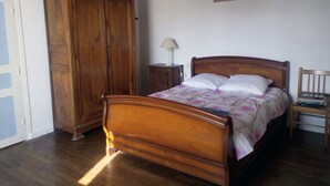 A bedroom with a wooden bed, a nightstand, a wooden wardrobe, and a small table with books. - Large home park, in a small Breton village 4 km from the sea  (Kerfot)