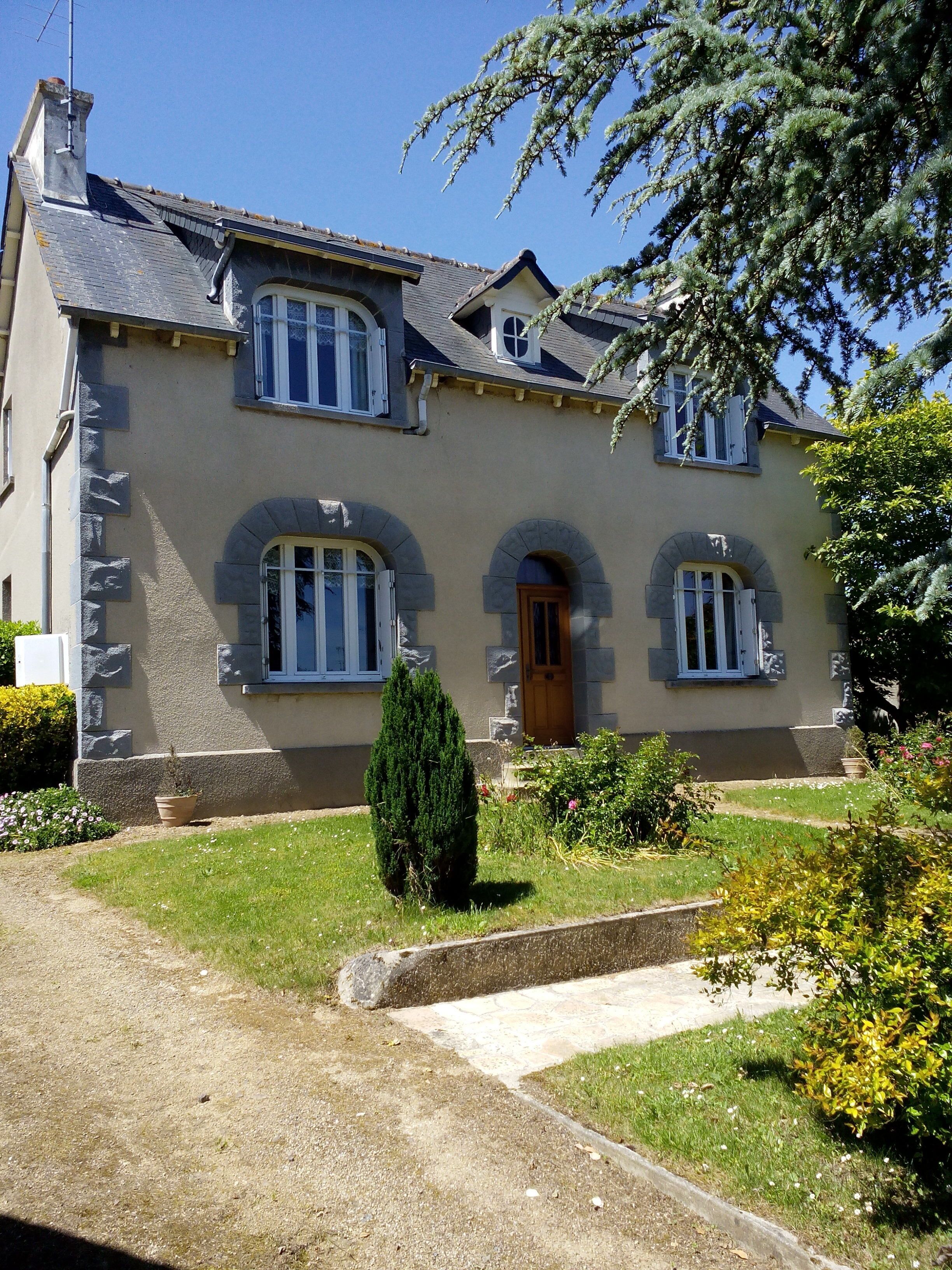 A two-story house with stone accents, a central entrance, and a well-maintained garden.