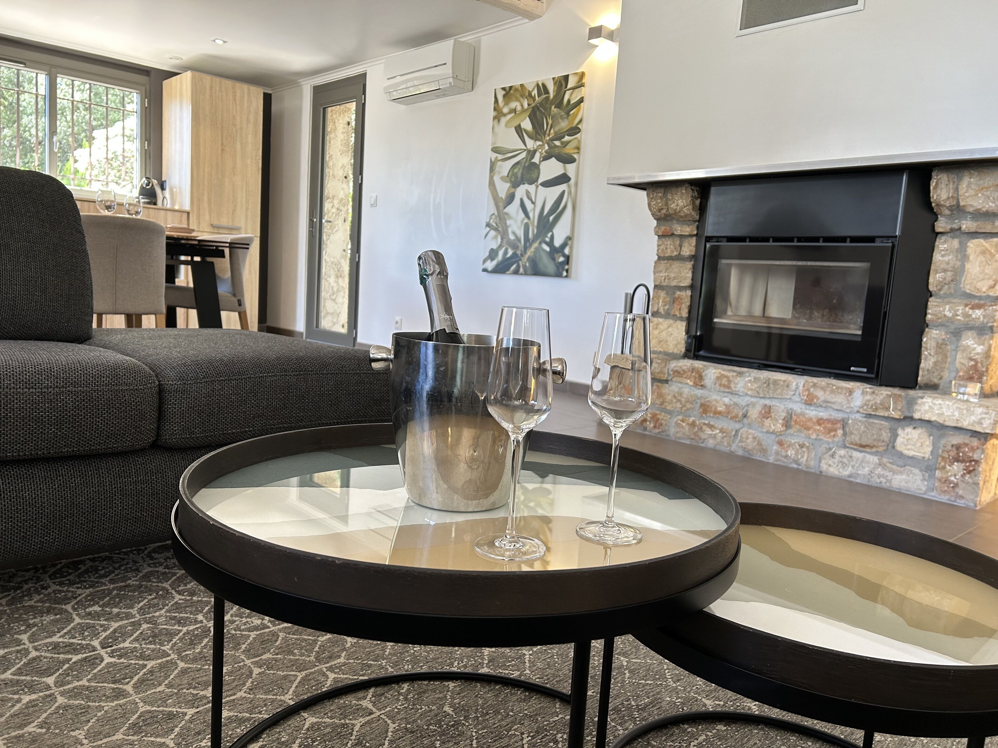 A modern living room with a stone fireplace, a glass coffee table, and a sofa.