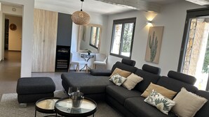Een moderne woonkamer met een modulaire bank, een glazen salontafel en een eethoek met een witte stoel en tafel.