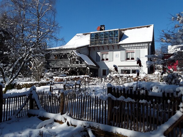 A snow-covered building with a balcony and a wooden fence in the foreground. - A cottage in a garden in Rougegoutte (Rougegoutte)