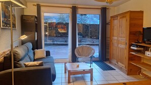 A cozy living room with a sofa, a wooden coffee table, a chair, and a TV on a wooden stand.
