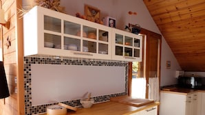 Una cocina con armarios blancos, encimera de madera y salpicadero de azulejos.