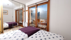 Un dormitorio con dos camas, un espejo grande y un balcón con vista a la montaña.