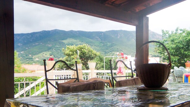 A table with a wicker basket and chairs, overlooking a mountainous landscape.