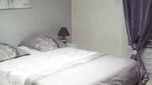A bedroom with a bed, pillows, a nightstand, a lamp, and a painting on the wall.