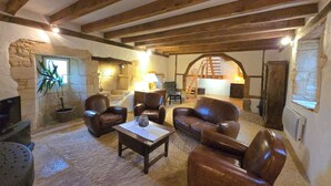 A rustic interior with stone walls, wooden beams, leather furniture, and a stone fireplace. - Cottage of charm and character, 220 m2, quiet, between Sarlat and Lascaux. (Archignac)