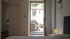 Una camera da letto con un letto, una porta che dà su un balcone e un tavolino con una lampada.