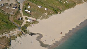 Vista aérea de una zona costera con playa, una carretera y varios edificios.