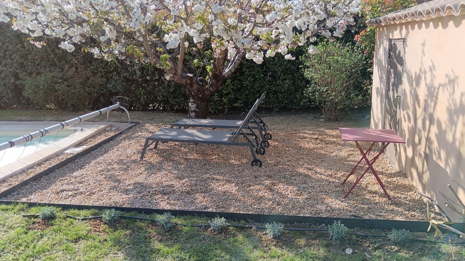 A garden area with two lounge chairs, a small table, and a poolside area.
