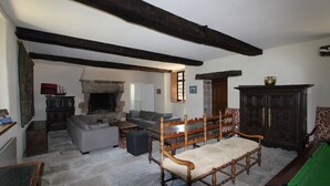 Un salon traditionnel avec une cheminée en pierre, un banc en bois, un canapé gris et une table de billard.