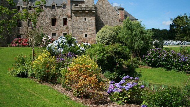 Un bâtiment en pierre avec un jardin à l’avant.