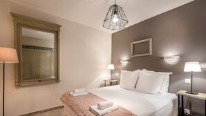 A hotel room with a large bed, two bedside lamps, a mirror, and a wooden nightstand.
