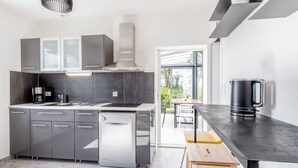 A modern kitchen with grey cabinets, a built-in dishwasher, and a coffee machine.