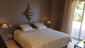 Ein ordentlich bezogenes Bett mit einem gemusterten Überwurf, zwei Nachttischlampen und einer Wanddekoration.