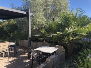 Relax in a serene outdoor space surrounded by lush greenery and a pergola.