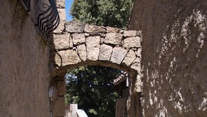 A stone pathway leading through an arched stone structure with steps ascending to a higher level.