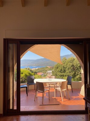 An outdoor patio with a table and chairs, offering a view of a mountainous landscape and a body of water. - Space, sun and freedom: 4 terraces, private garden, air-conditioned rooms.  (Propriano)