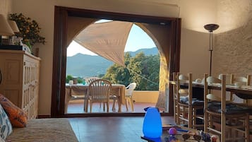 Une chambre avec vue sur les montagnes, un coin repas avec des chaises et une table, et un lit avec des oreillers.
