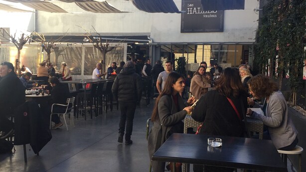 An outdoor dining area with tables and chairs, a covered seating area, and a building with a sign reading "Les HALLEUS Vauban". - T2 ground floor,  air conditioning placed in February 2023:)free public car park (Perpignan)
