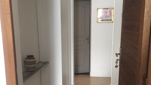 A hallway with a wooden floor, a white door, and a shelf with a decorative item. - T2 ground floor,  air conditioning placed in February 2023:)free public car park (Perpignan)