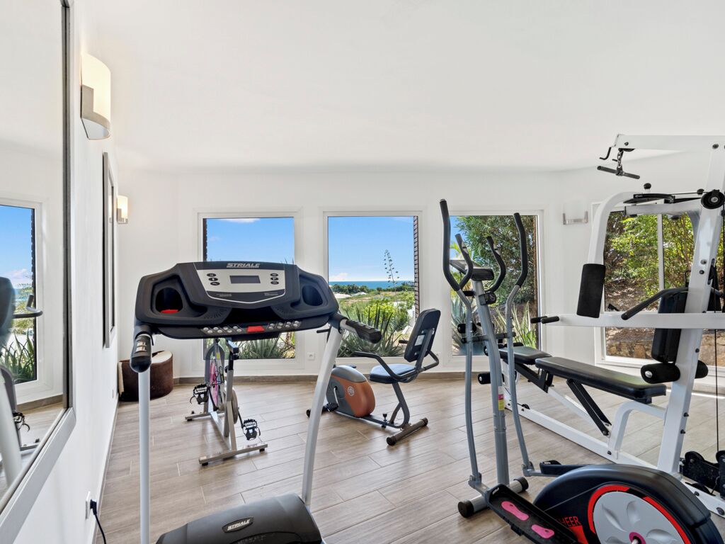 A home gym with cardio equipment, weight machines, and a bench.