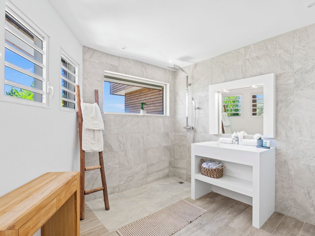 Een moderne badkamer met een witte wastafel, een grote spiegel en een douchehoek.