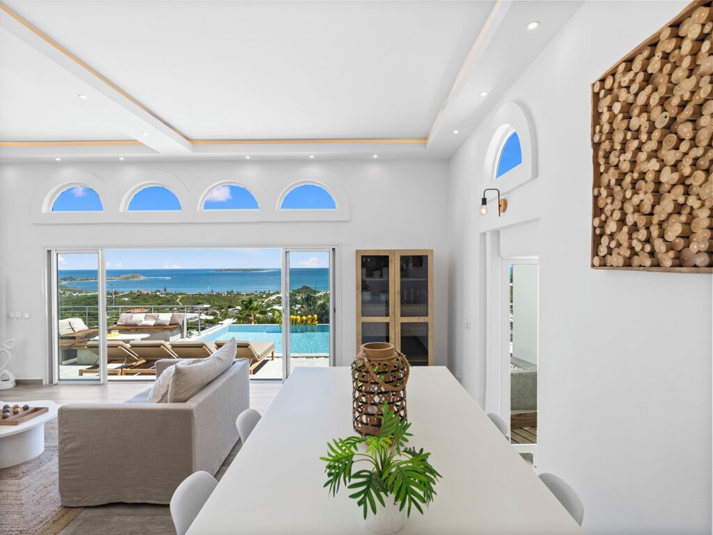 A modern interior with a dining area, a view of the ocean, and a decorative wall.