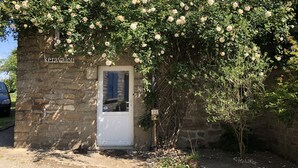 A stone building with a white door, covered in blooming white roses, and a sign reading "keravalou". - Country house heated pool 15 minutes from the Gulf of Morbihan (Sulniac)