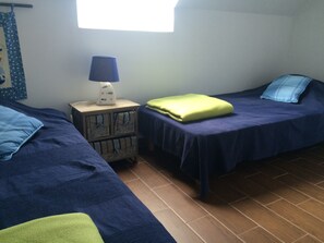 Huoneessa on kaksi sänkyä, yöpöytä, jossa on lamppu, ja ikkuna.