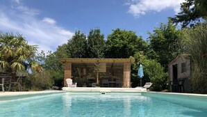 A clear swimming pool with lounge chairs and a covered seating area. - Country house heated pool 15 minutes from the Gulf of Morbihan (Sulniac)