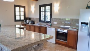 Una cocina moderna con encimeras de granito, armarios de madera, horno Bosch y lavavajillas integrado.
