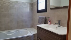 Een bad/douchecombinatie, een haardroger, handdoeken, zeep