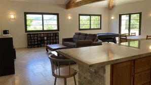 Amplia sala de estar con mesa de billar, sofá y zona de bar.