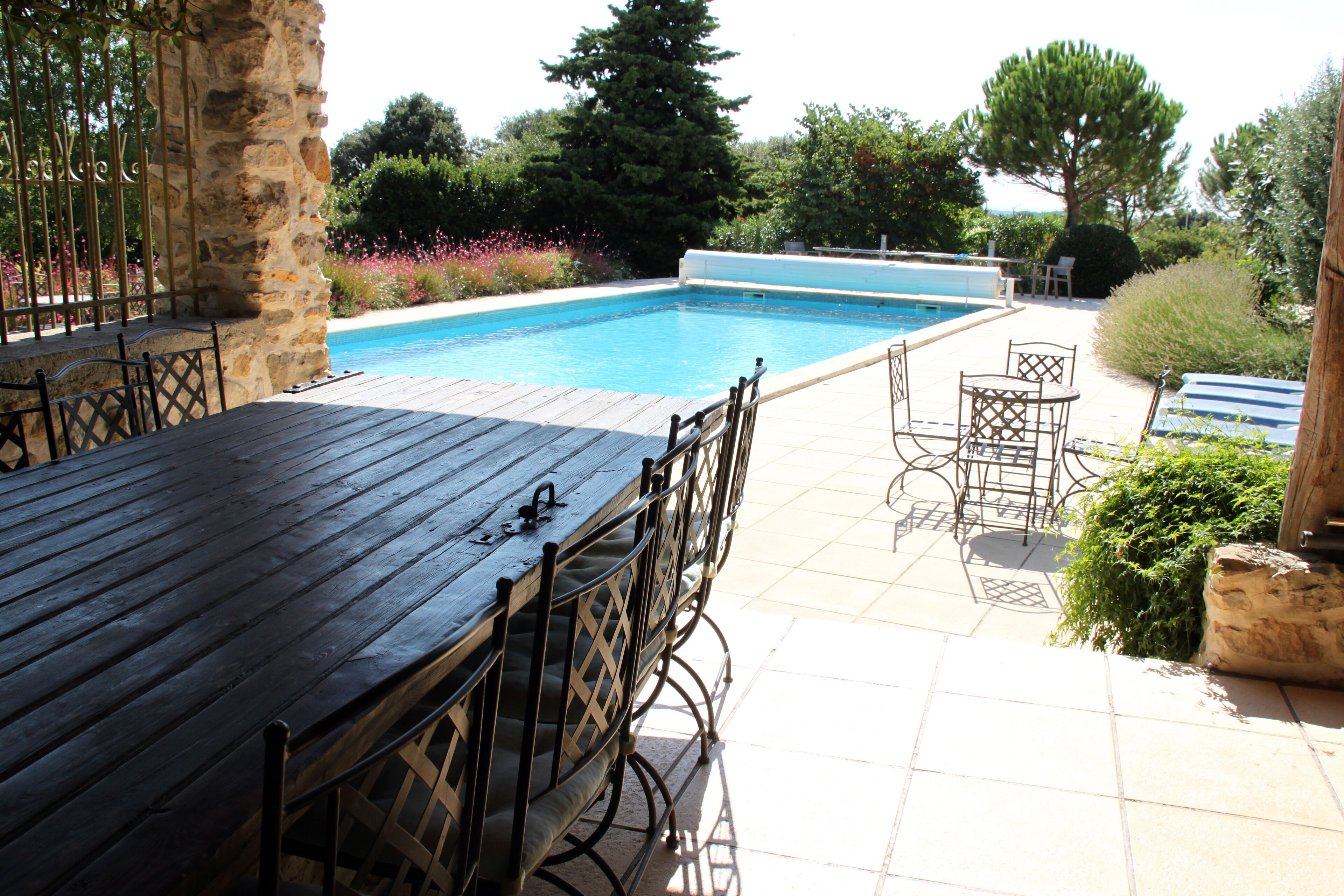 Ein Poolbereich mit Holzterrasse, Metallstühlen und einer Steinwand.