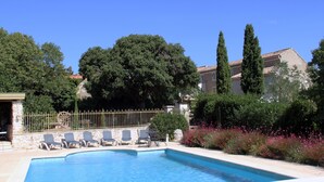 A swimming pool with lounge chairs and a stone wall.