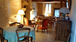 A cozy dining area with a table set for two, a red chair, and a wooden cabinet. - Charming medieval house in the heart of Flavigny-sur-Ozerain (Flavigny-Sur-Ozerain)