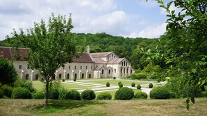 A historic building with a symmetrical garden layout, featuring a central lawn, manicured hedges, and a traditional architectural style. - Charming medieval house in the heart of Flavigny-sur-Ozerain (Flavigny-Sur-Ozerain)
