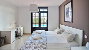 A bedroom with a bed, a desk, and a chair. There is a door leading to a balcony. - Luxury villa with private heated pool, WIFI, views of the sea and volcanoes (TIAS)