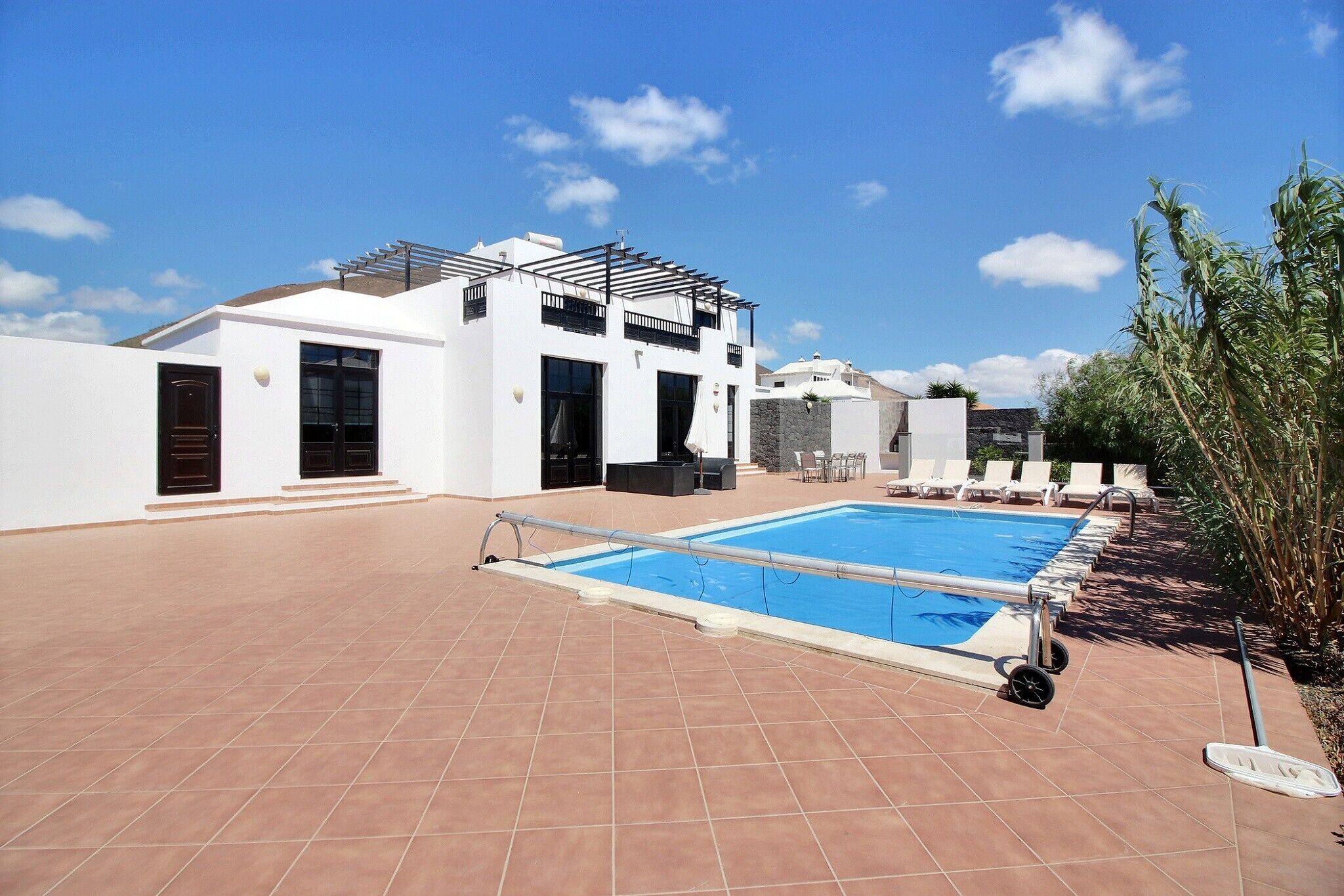 A modern house with a swimming pool, outdoor furniture, and a pergola.