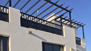 An outdoor seating area with a sofa and chairs, a table with a bowl of fruit, and a pergola structure. - Luxury villa with private heated pool, WIFI, views of the sea and volcanoes (TIAS)