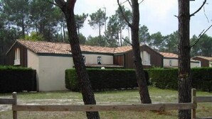 A row of cabins with tiled roofs, surrounded by trees and a wooden fence. - A cozy little nest in Biscarosse Lac, Superb high-end full option duplex (Biscarrosse)