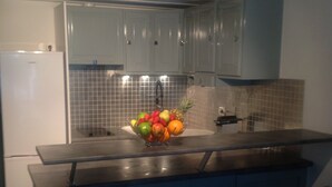 A kitchen with a fruit bowl on the counter, two bar stools, and a refrigerator. - A cozy little nest in Biscarosse Lac, Superb high-end full option duplex (Biscarrosse)