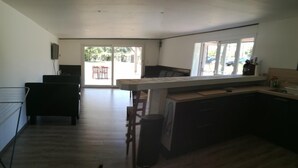A modern kitchen with a central island, a dining area with chairs, and a large sliding glass door leading to an outdoor patio.